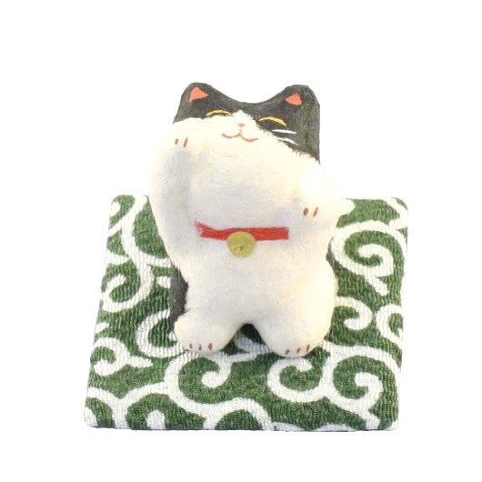 Gatto giapponese, Maneki Neko, letteralmente " gatto che chiama " ,tipico  porta fortuna, spesso utilizzato anche nelle attività commerciali per attirare clienti, fortuna e denaro, in base alla zampa che tiene alzata. Piccolo gatto porta fortuna di colore bianco con macchie nere, comodamente appoggiato su di un morbido cuscino, occhi chiusi e dolce sorriso, con una zampina alzata in segno di richiamo.