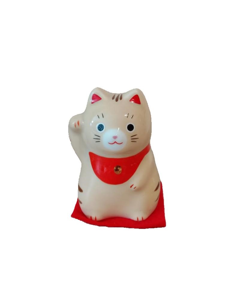 Gatto giapponese, Maneki Neko, letteralmente "gatto che chiama" ,tipico  porta fortuna, spesso utilizzato anche nelle attività commerciali per attirare clienti, fortuna e denaro, in base alla zampa che tiene alzata. Piccolo gattino della fortuna beige con strisce arancioni , che siede sopra ad un tappetino rosso, con un bavaglino al collo di colore sempre rosso con una campanellina color oro.